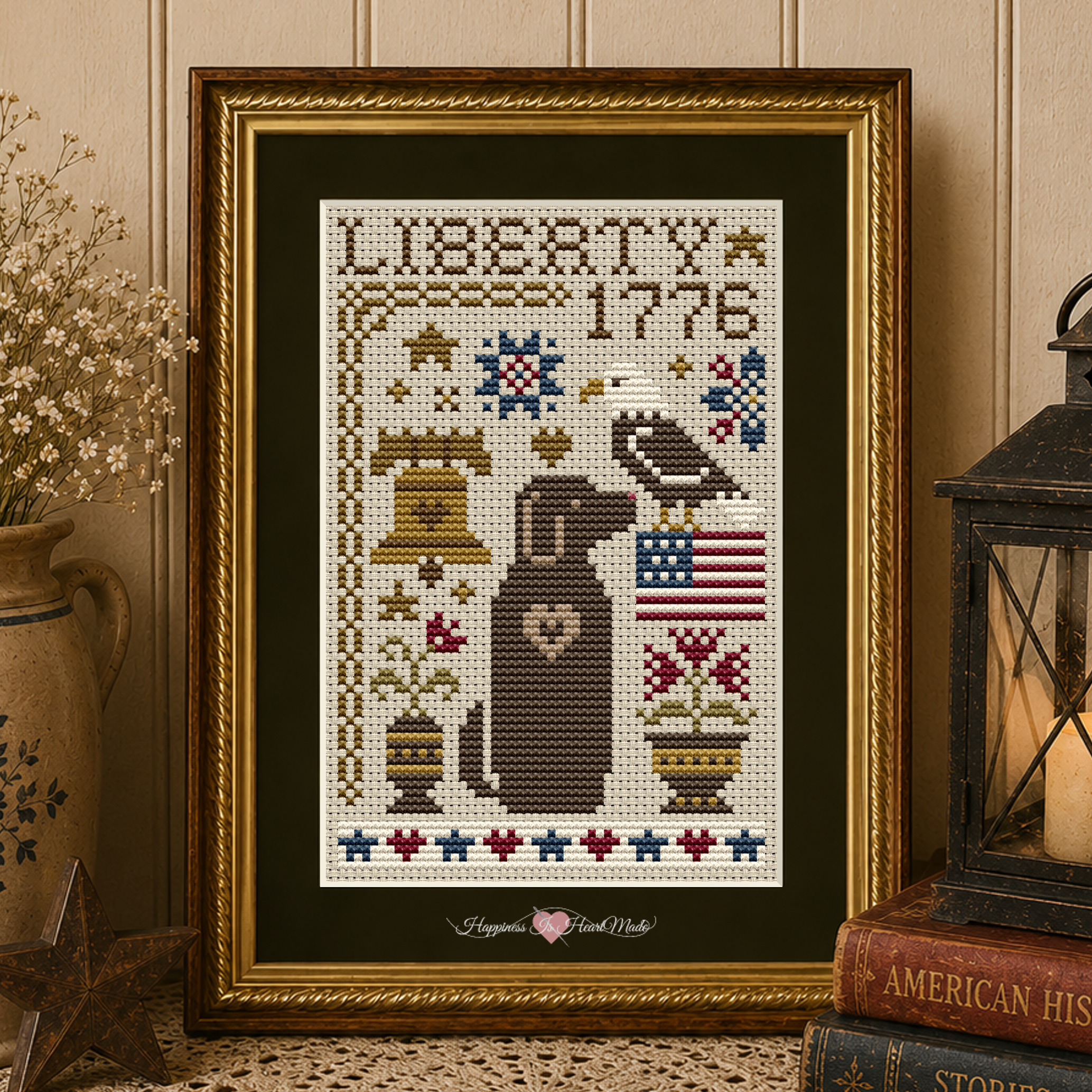 Liberty Dog Cross Stitch Pattern 6587 from the Dog Days Series by Happiness Is HeartMade. A patriotic counted cross stitch design by Christy Shuhy Ortiz featuring a brown Labrador Retriever-style dog beneath the words "Liberty 1776," surrounded by a bald eagle, American flag, Liberty Bell, flowers, hearts, and stars.